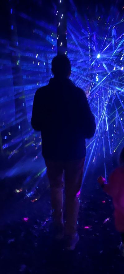 Brent Cody, seen from behind in silhouette, walking into a burst of blue laser light