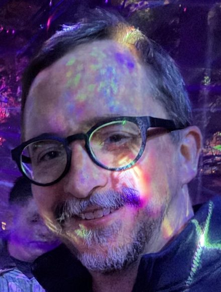 Close-up of Brent Cody smiling, his face dappled with colored light